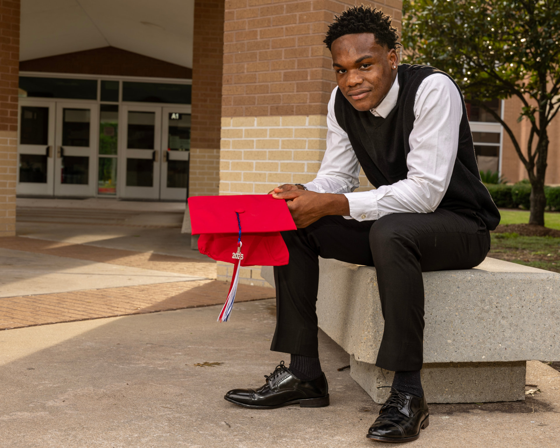 AJ on campus holding his 2025 graduation cap