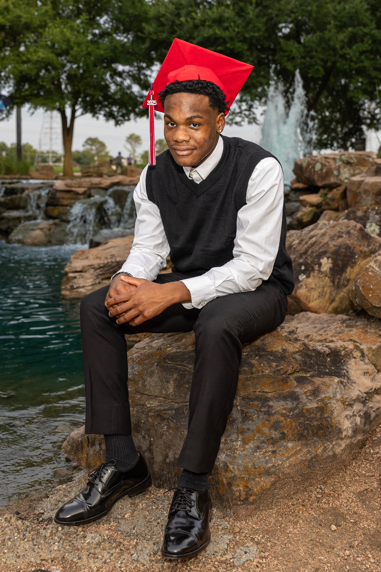 AJ wearing a red graduation cap and gown
